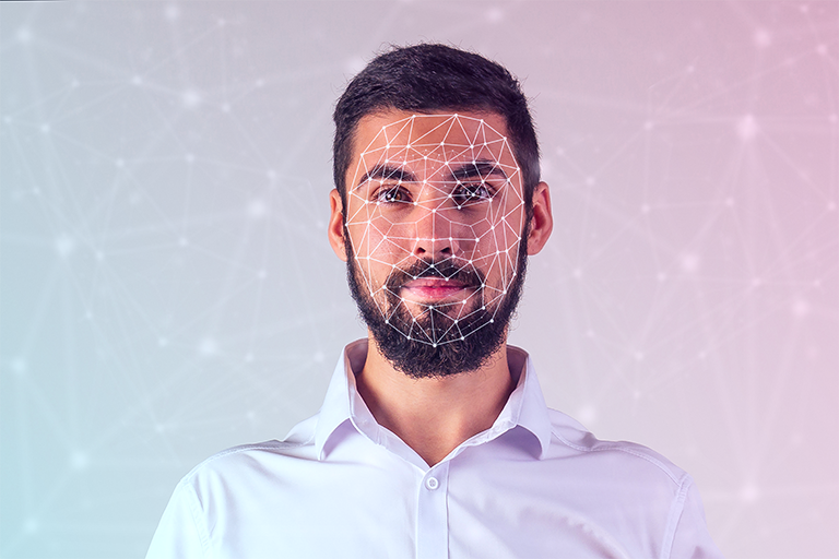 Homem brance de barba e camisa social branca tendo a face escaneada por pontos de biometrial facial
